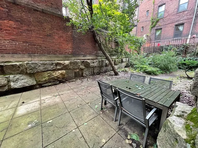 a roof deck with table and chairs and potted plants