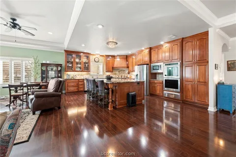 a living room with stainless steel appliances furniture a rug and a kitchen view