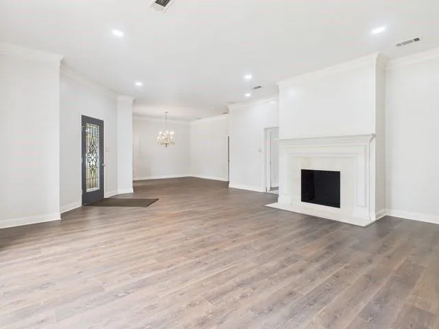 a view of an empty room with wooden floor and a fireplace
