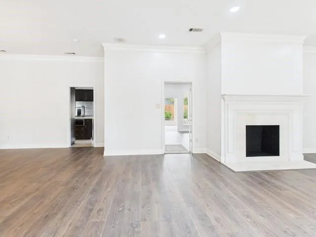 a view of an empty room with wooden floor and a fireplace
