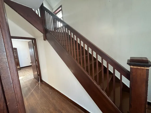 a view of staircase with lots of frames on wall and wooden floor