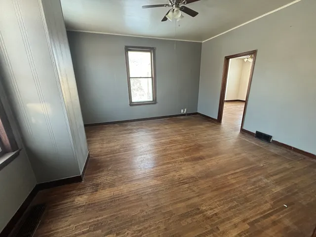 an empty room with wooden floor and windows