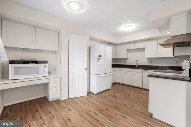 a kitchen with granite countertop white cabinets and white appliances