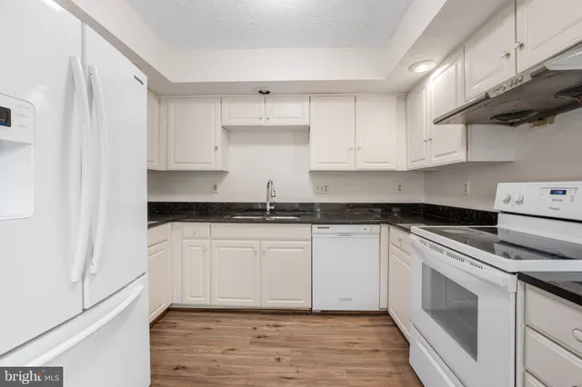 a kitchen with granite countertop white cabinets and white appliances