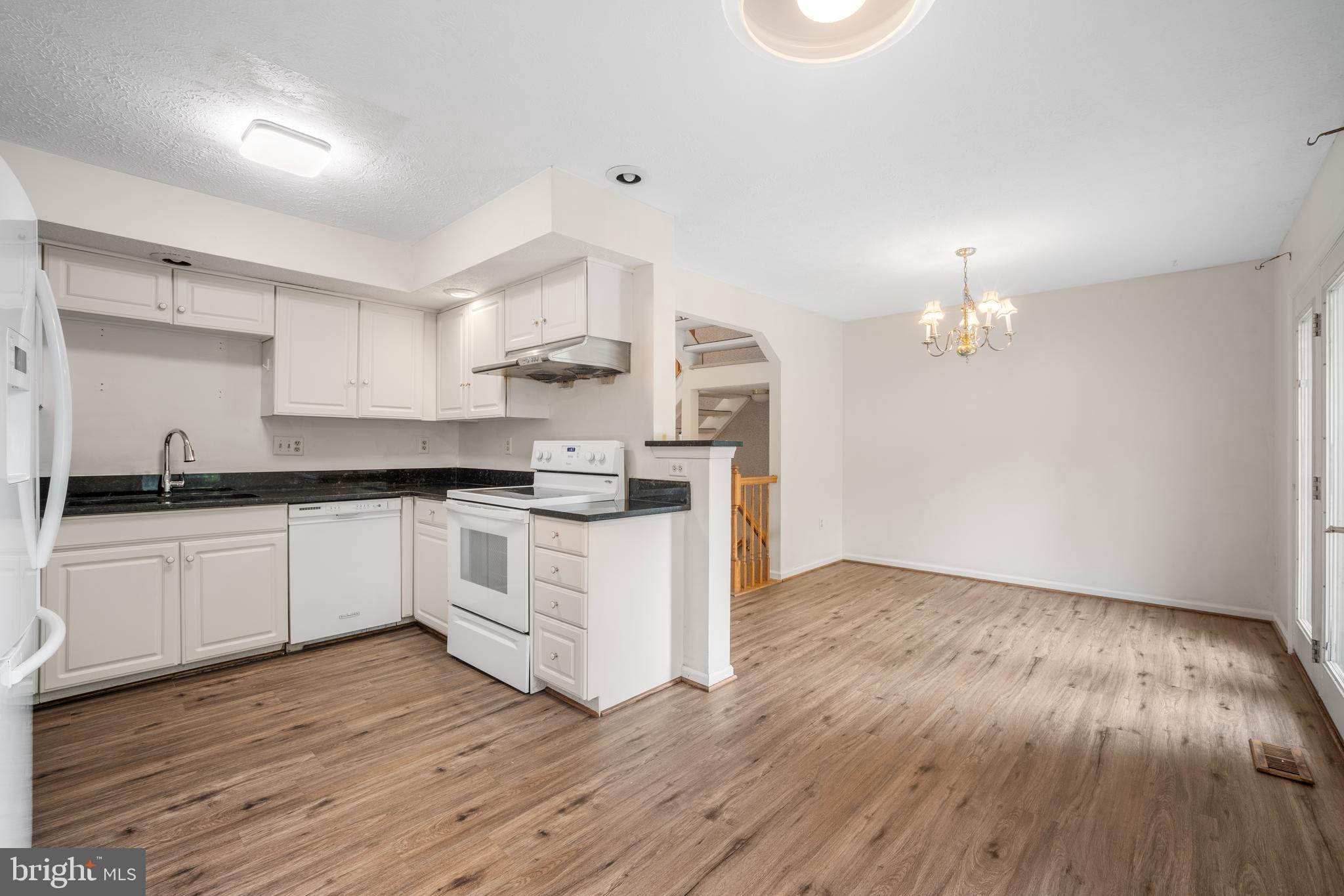 5522 April Journey, Unit 11 Columbia, MD 21044 - Photo 14 of 34 a kitchen with wooden floors and white cabinets
