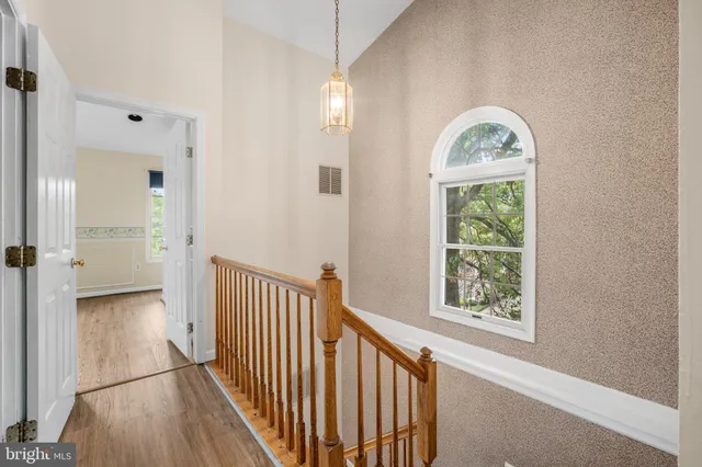 a view of a hallway with wooden floor and a chandelier