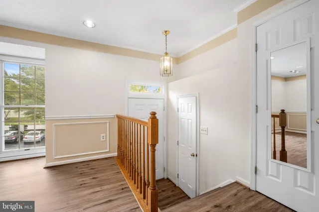 a view of a hallway with wooden floor and a bathroom