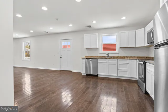 a kitchen with stainless steel appliances granite countertop a refrigerator sink and white cabinets
