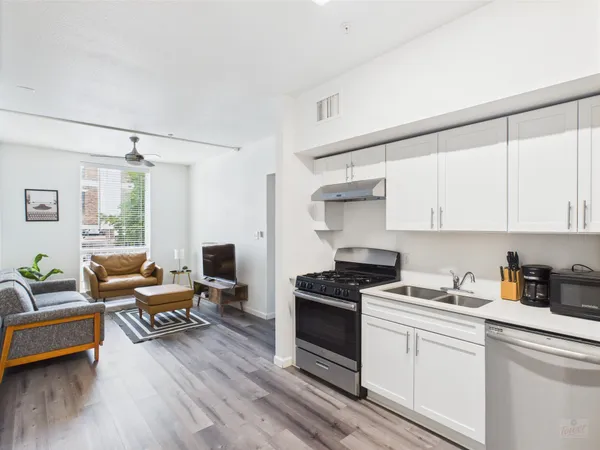 a kitchen with stainless steel appliances granite countertop a stove and white cabinets with wooden floor