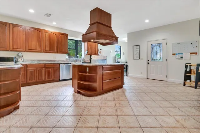a large kitchen with stainless steel appliances a stove a sink and a refrigerator