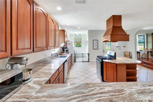a large kitchen with stainless steel appliances granite countertop a stove a sink and a refrigerator