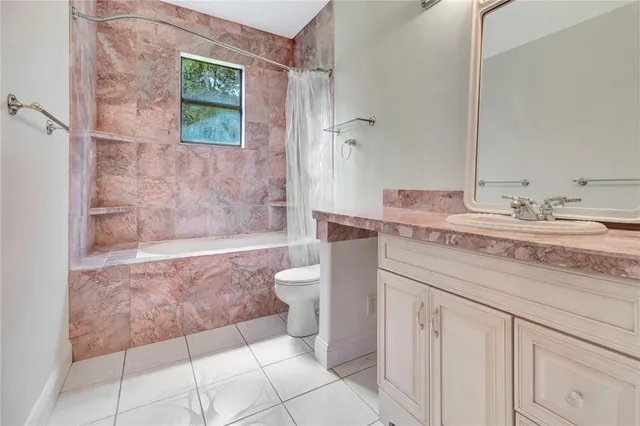 a bathroom with a granite countertop sink a toilet a mirror and bathtub