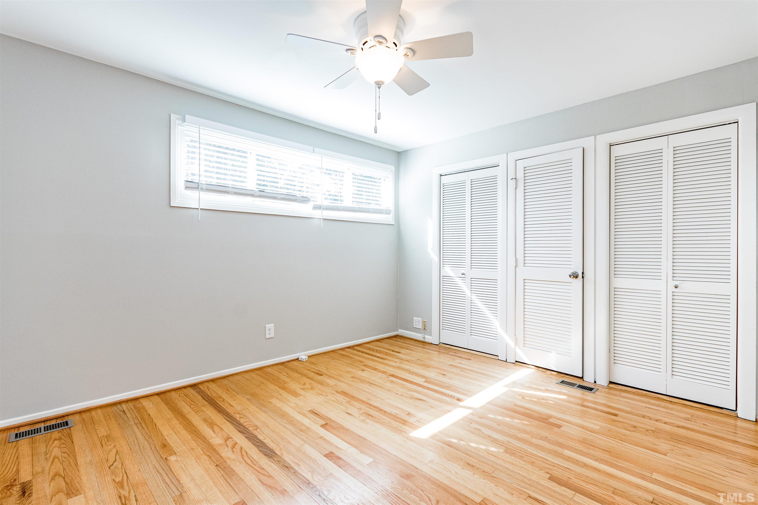 3412 Bradley Place Raleigh, NC 27607 - Photo 18 of 28 an empty room with wooden floor chandelier fan and windows