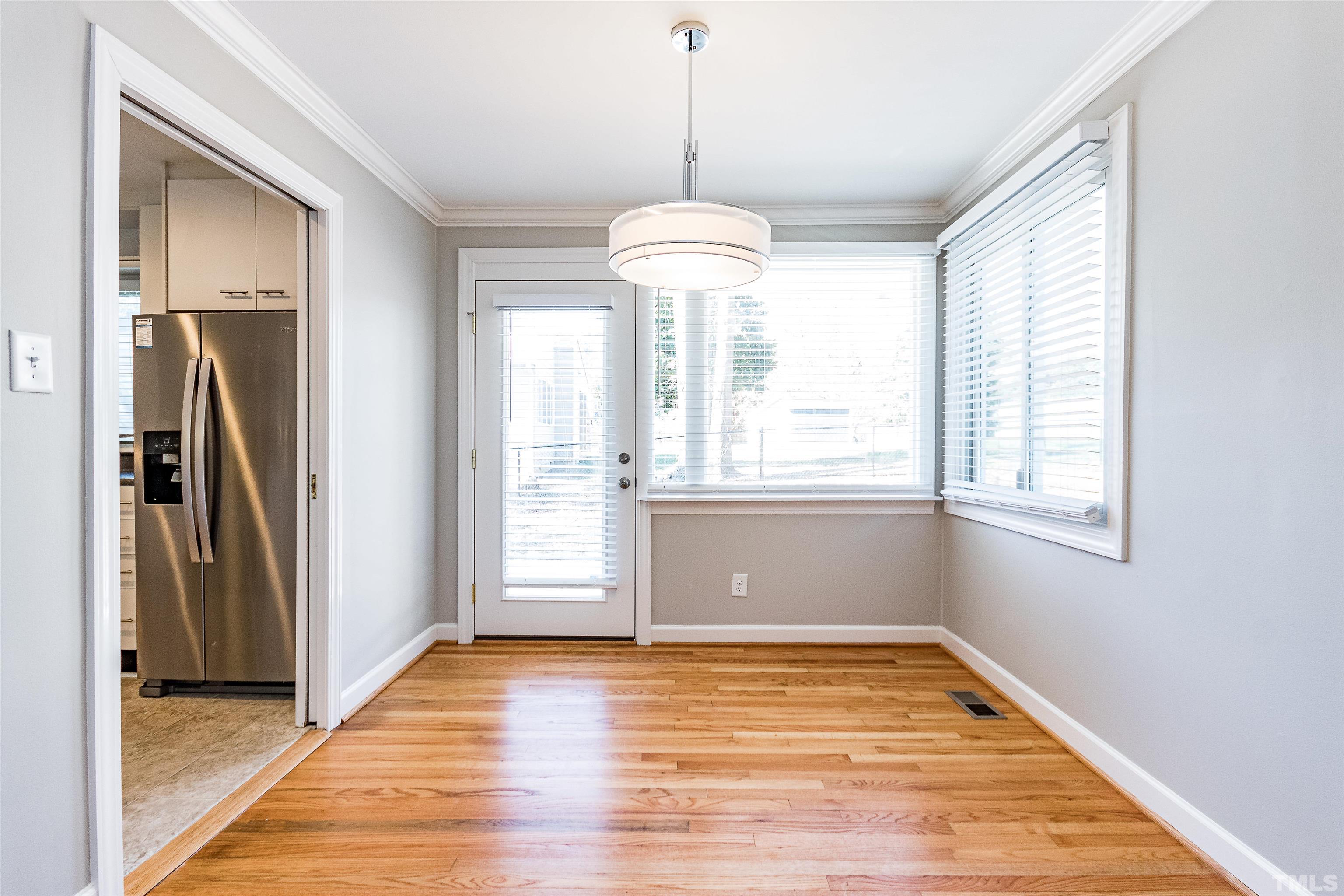 3412 Bradley Place Raleigh, NC 27607 - Photo 10 of 28 a view of empty room with wooden floor and large window