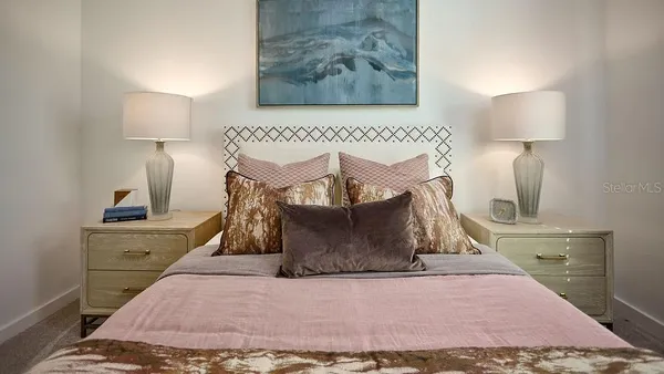 a view of a bedroom with a bed and lamp on dresser