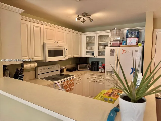 a kitchen with stainless steel appliances granite countertop a refrigerator a stove and a sink with wooden floor
