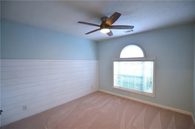an empty room with a window and a ceiling fan