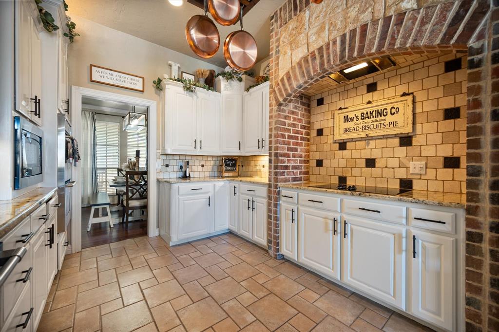 212 Ashmore Place Haslet, TX 76052 - Photo 16 of 39 Kitchen featuring white cabinetry, tasteful backsplash, premium range hood, and light stone counters