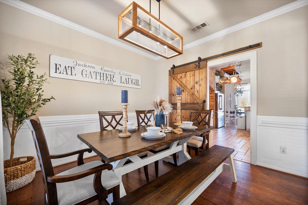 212 Ashmore Place Haslet, TX 76052 - Photo 18 of 39 Dining area featuring a wainscoted wall, ornamental molding, a decorative wall, dark wood-type flooring, and a barn door