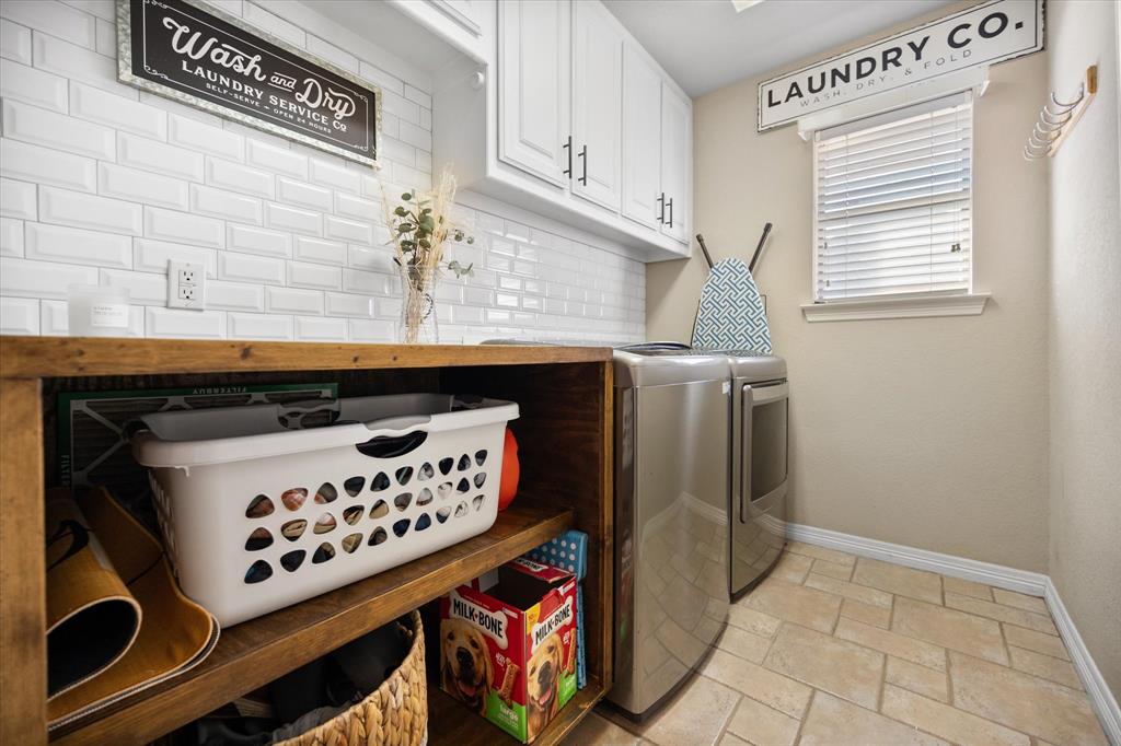 212 Ashmore Place Haslet, TX 76052 - Photo 32 of 39 Laundry area featuring stone tile floors, cabinet space, and independent washer and dryer