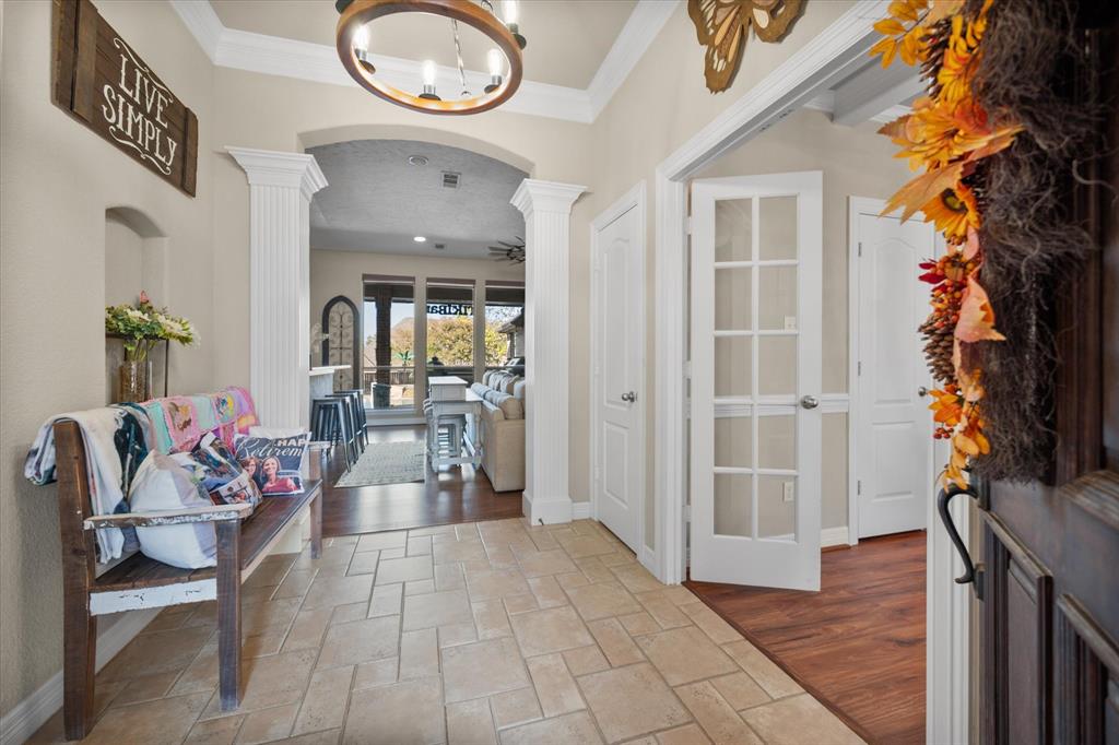 212 Ashmore Place Haslet, TX 76052 - Photo 6 of 39 Foyer entrance with stone tile floors, arched walkways, ceiling fan, ornamental molding, and decorative columns
