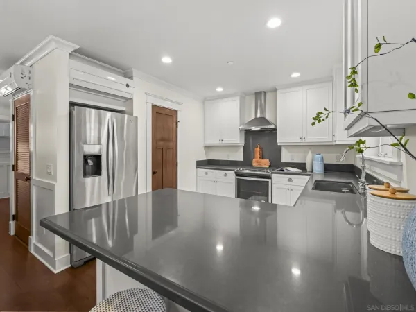 a kitchen with stainless steel appliances granite countertop a refrigerator a stove and a sink with wooden floor