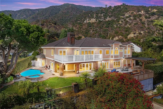 a aerial view of a house with swimming pool and trees in the background