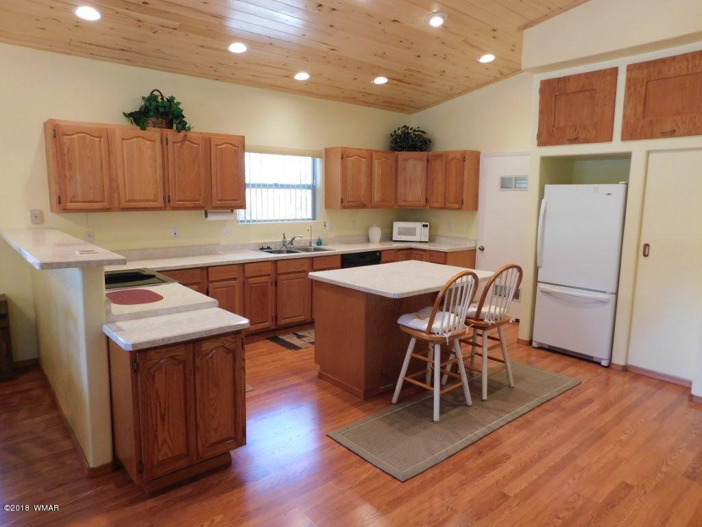 2968 Monica Road Overgaard, AZ 85933 - Photo 16 of 29 a kitchen with a table chairs refrigerator and wooden floor