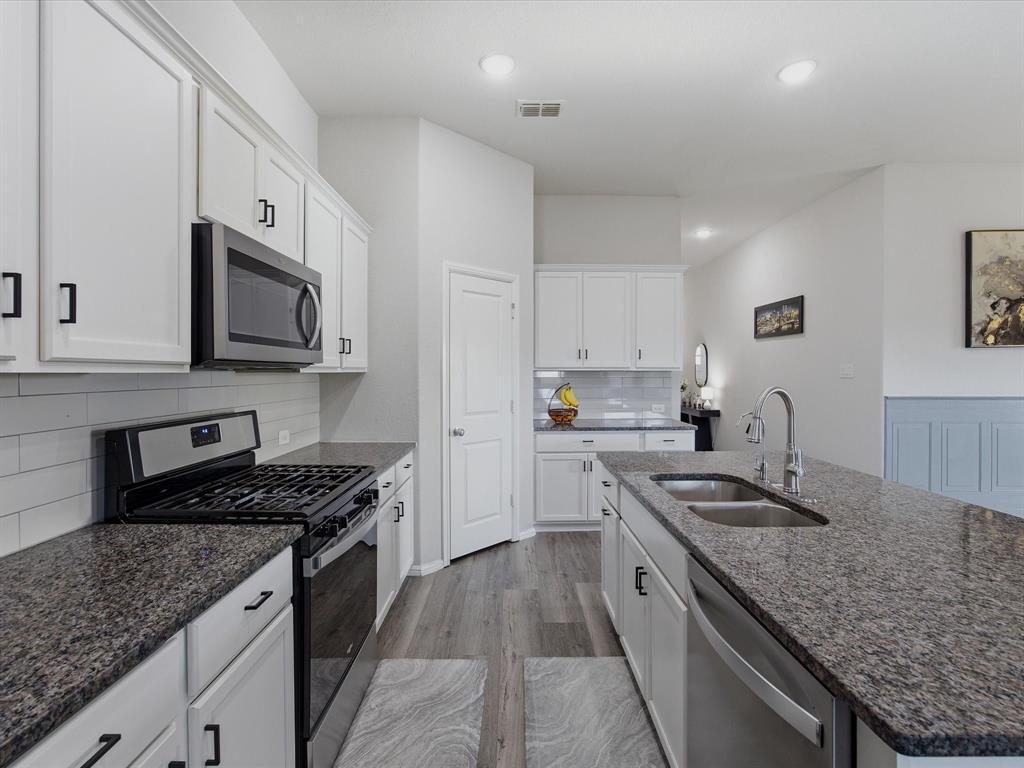 6000 Sutton Fields Trail Aubrey, TX 76227 - Photo 11 of 40 Kitchen with stainless steel appliances, dark stone counters, white cabinetry, wood finished floors, and recessed lighting