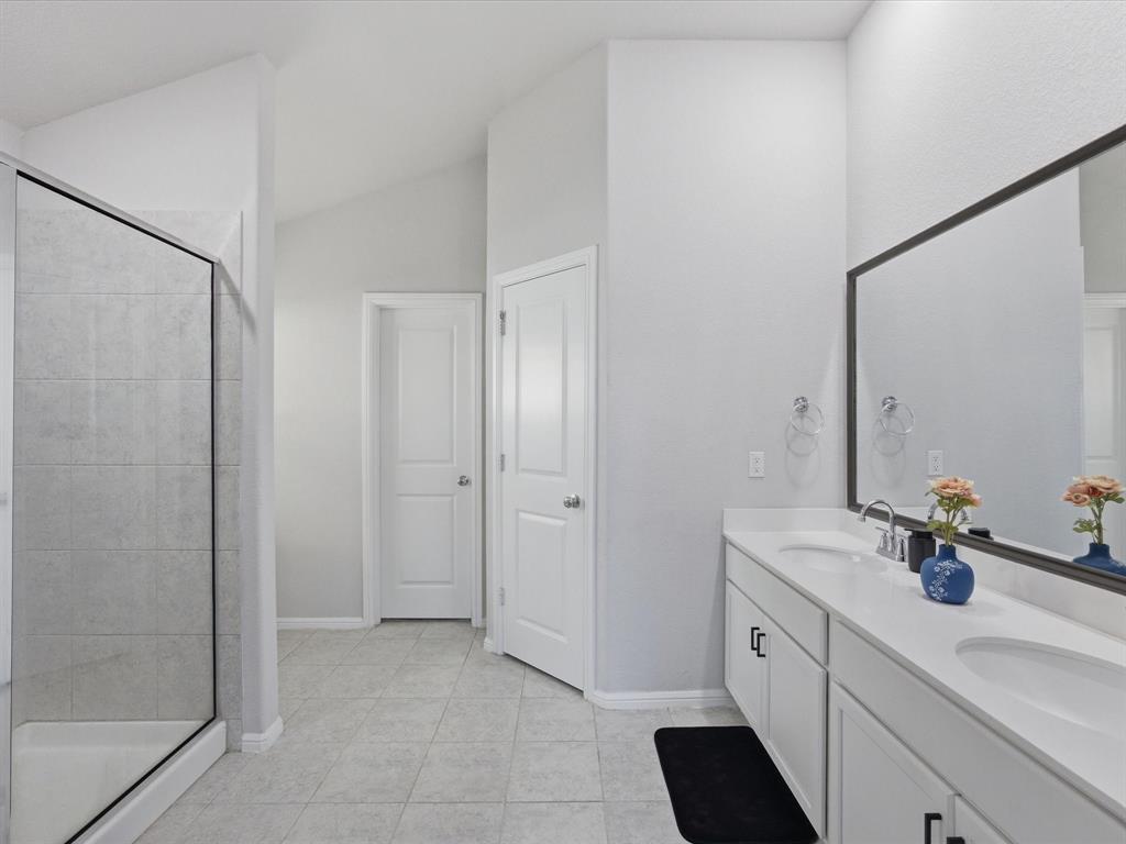 6000 Sutton Fields Trail Aubrey, TX 76227 - Photo 18 of 40 Primary bath featuring double vanity, a stall shower, light tile patterned floors, and lofted ceiling