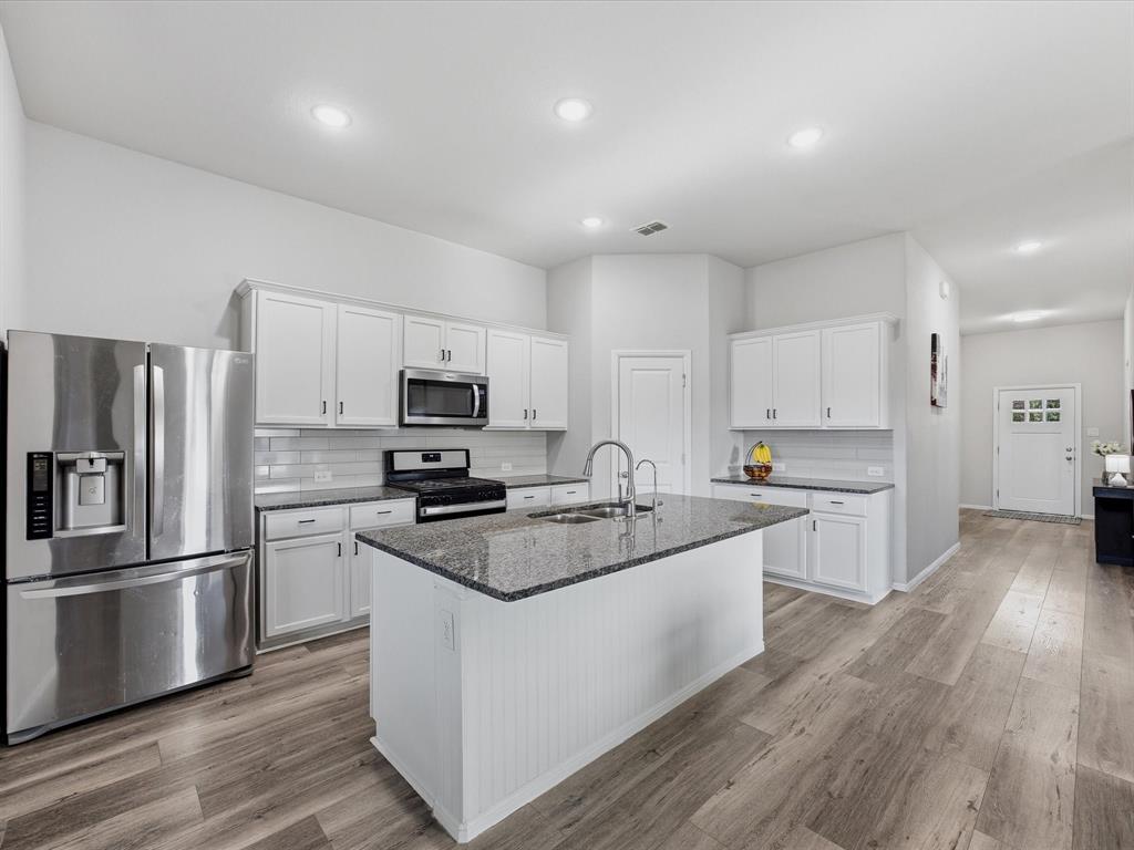 6000 Sutton Fields Trail Aubrey, TX 76227 - Photo 9 of 40 Kitchen with stainless steel appliances, white cabinets, tasteful backsplash, and recessed lighting