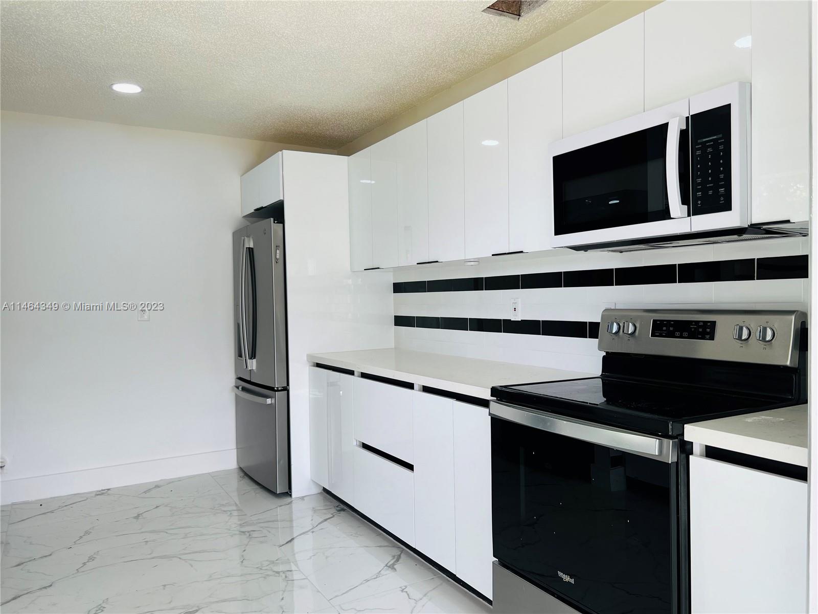11301 Southwest 203rd Terrace Miami, FL 33189 - Photo 12 of 51 a kitchen with stainless steel appliances a stove microwave and refrigerator