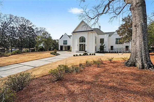 a view of white house with a yard covered with snow and trees