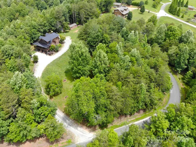 an aerial view of residential house with outdoor space and trees all around