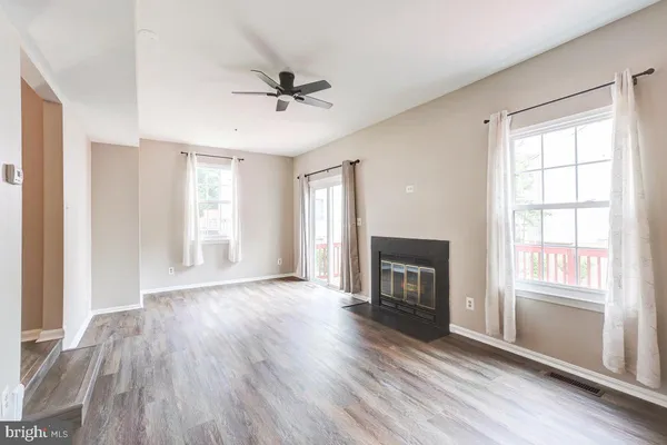 a view of an empty room with wooden floor fireplace and a window