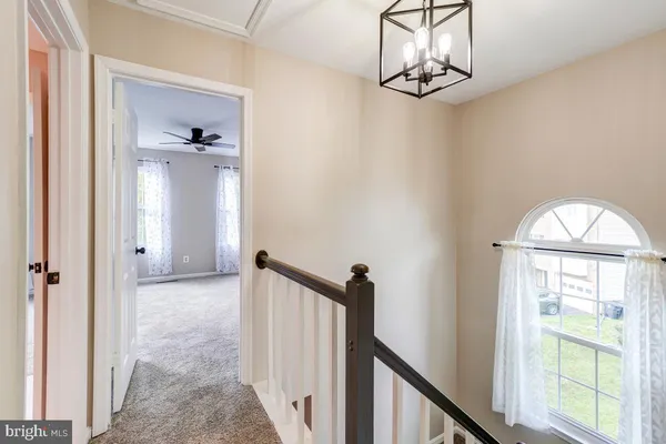 a view of a hallway with windows and chandelier