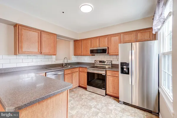 a kitchen with stainless steel appliances granite countertop a refrigerator sink and stove