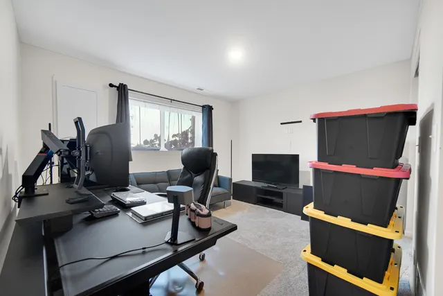 a work room with furniture a flat screen tv and a window