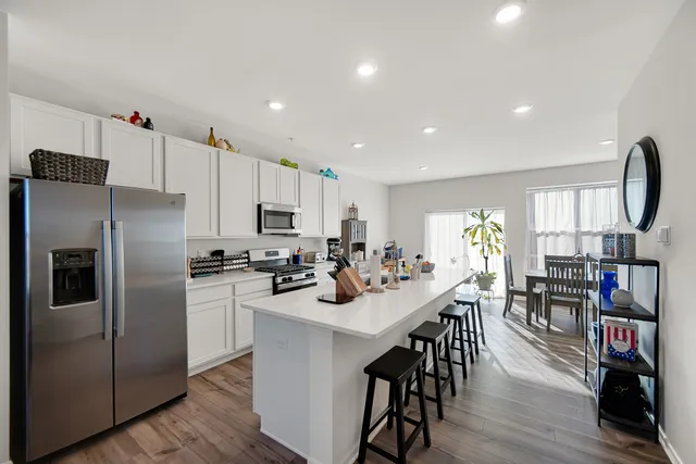 a kitchen with stainless steel appliances a refrigerator a stove a sink dishwasher and a dining table with wooden floor