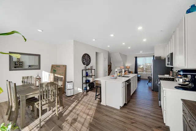 a living room with stainless steel appliances furniture and a kitchen view