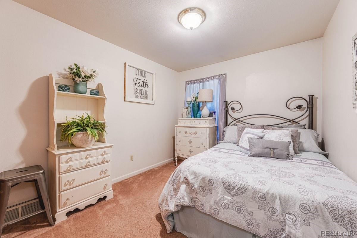 2166 35th Ave Court, Unit 14 Greeley, CO 80634 - Photo 23 of 33 a bedroom with a bed and a potted plant on dresser