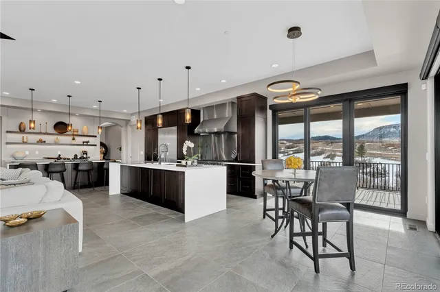 a kitchen with stainless steel appliances kitchen island granite countertop a table chairs sink and cabinets