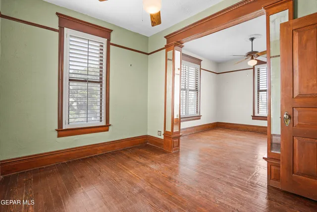 an empty room with wooden floor fan and windows