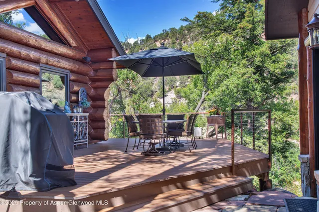 a view of patio with table and chairs under an umbrella with a small yard