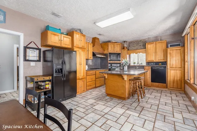 a kitchen with stainless steel appliances granite countertop a refrigerator a stove a sink a dining table and chairs