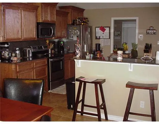 a kitchen with stainless steel appliances kitchen island granite countertop a refrigerator a stove top oven a sink and dishwasher