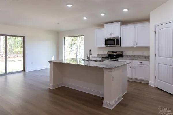 a kitchen with granite countertop white cabinets and appliances