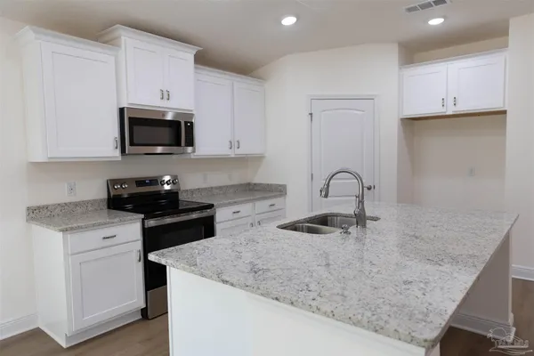 a kitchen with granite countertop white cabinets and stainless steel appliances