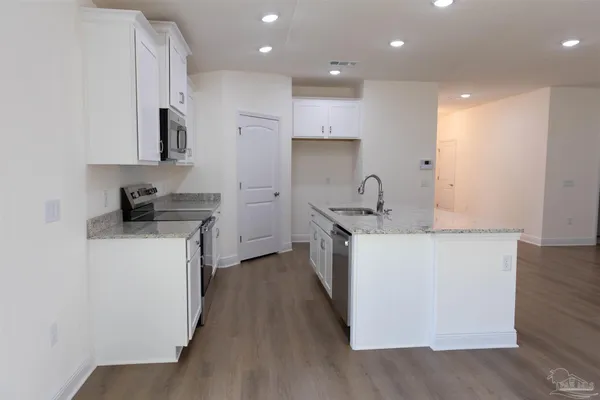 a kitchen with kitchen island granite countertop a sink and a stove top oven