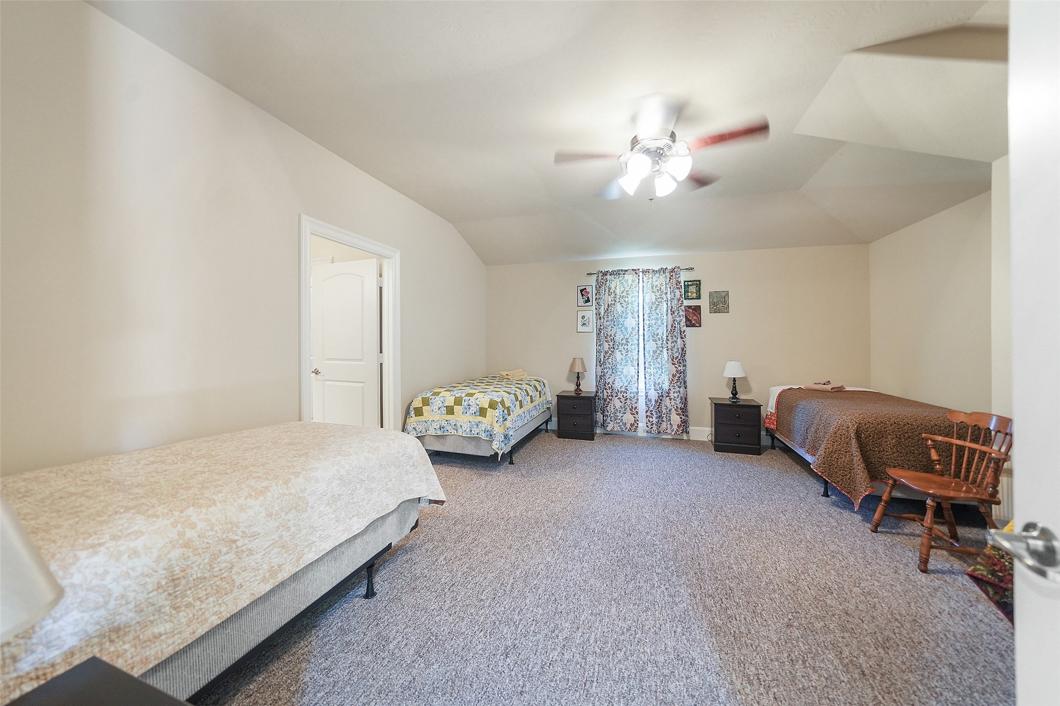 26250 B Riley Road Waller, TX 77484 - Photo 23 of 45 Expansive upstairs bedroom featuring multiple beds, carpeted flooring, a ceiling fan, and an attached full bathroom, ideal for group lodging.